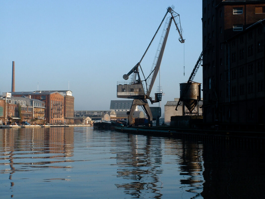 Foto: Kran im münsteraner Hafen Blick übers Wasser auf den münsteraner Hafen vom Hafenplatz aus. Auf der rechten Seite sieht man einen alten Kran stehen.