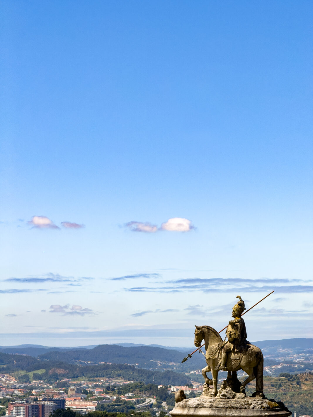 Foto: Wachsamer Blick auf Braga. Vor der Basilica Bom Jesus do Monte in Braga steht eine Reiterfigur, die über die weit unten liegende Stadt blickt.
