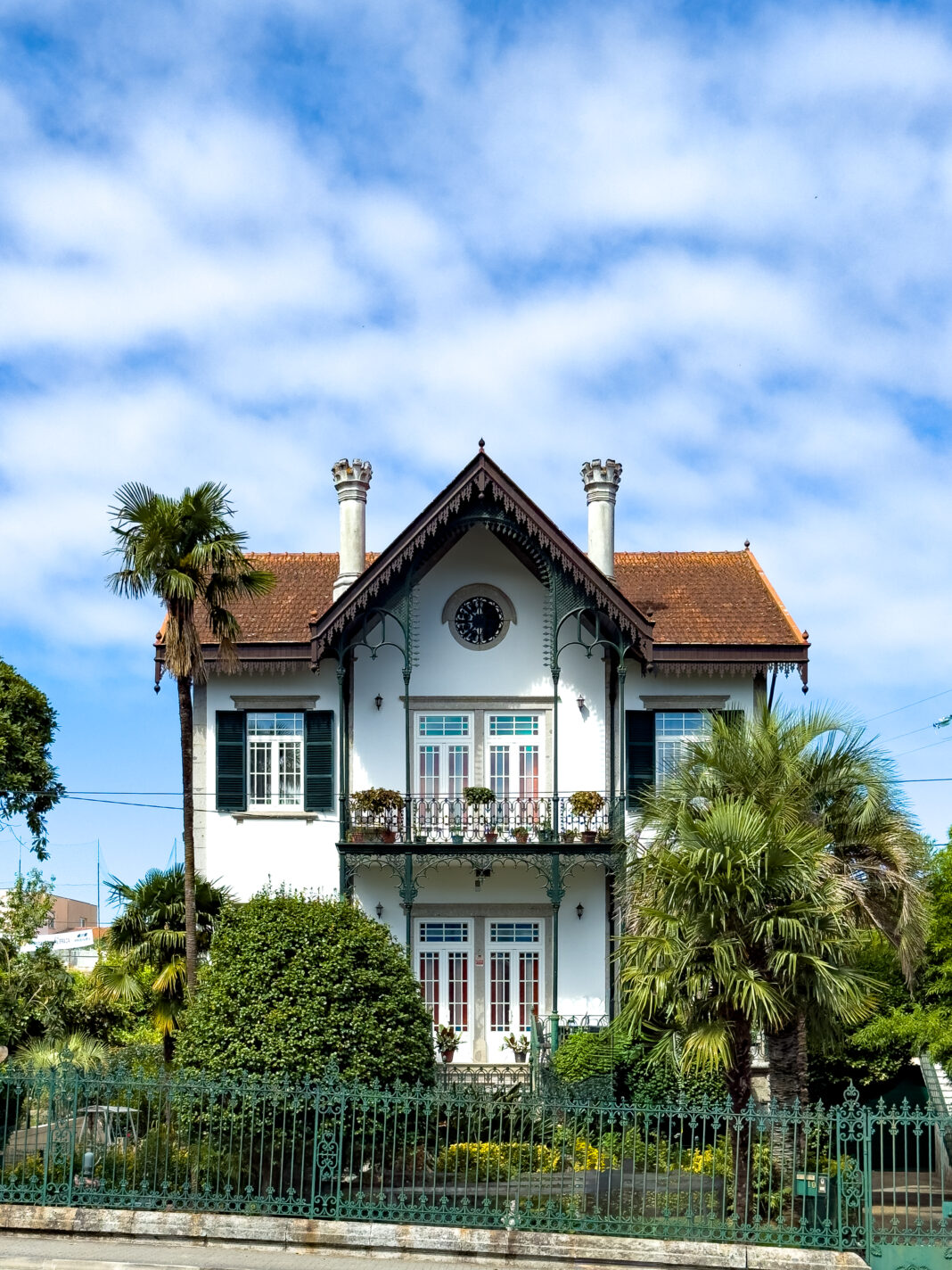 Schöne Villa mit viel Grünzeug drumrum vor blauem Himmel mit lockerer Bewölkung.