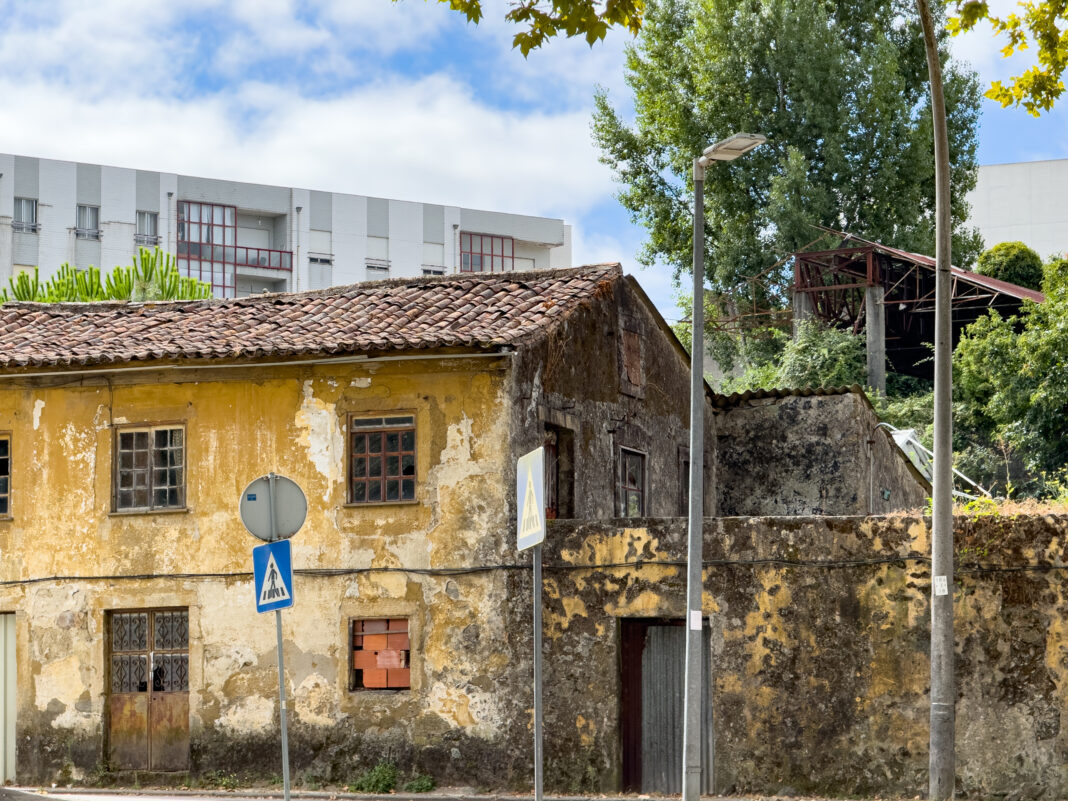 Foto: Alt vor neu in Braga. Man sieht ein verfallenes altes Haus vor einem moderneren aber nicht unbedingt schönerem Hochhaus.