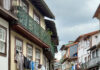 Foto: Gasse in Guimarães Foto: Gasse in Guimarães. Blick eine Gasse entlang, die eine Linkskurve nimmt. Links und rechts stehen dicht an dicht alte Häuschen. die Wäsche, Fahnen udn Balkone an der Fassade haben.